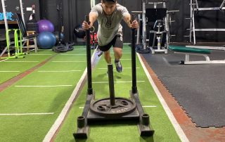 Man pushes weighted sled through gym